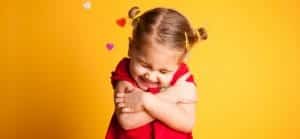 A little girl wearing a red dress and hugging herself