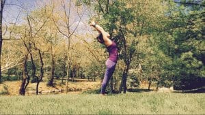 Woman in purple doing the standing back bend pose outdoor